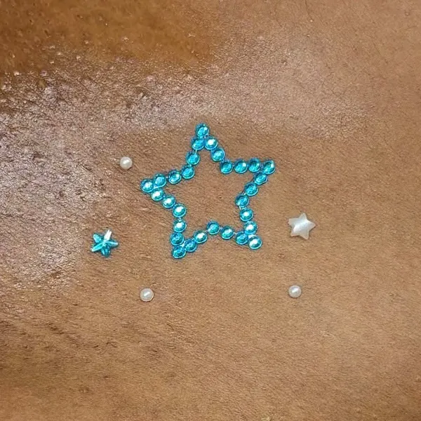 Une étoile de strass turquoise et des perles nacrées posées sur le maillot, après le soin